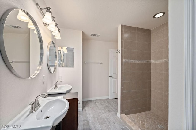 bathroom with vanity, hardwood / wood-style floors, and a tile shower