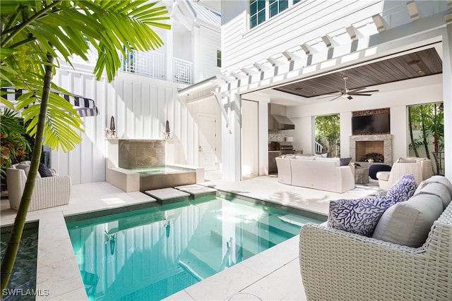 view of swimming pool with an outdoor living space with a fireplace, ceiling fan, and a patio