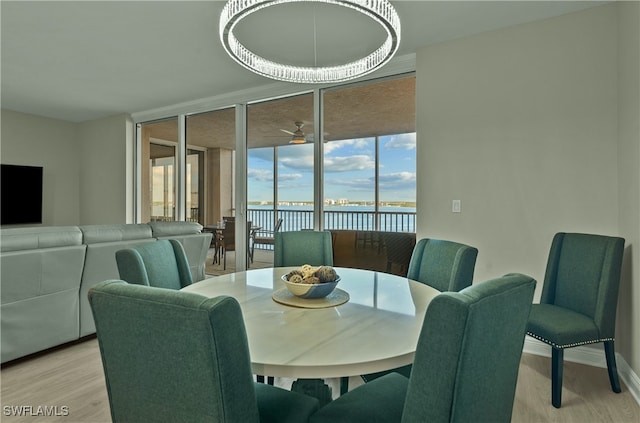 dining room featuring a chandelier, a water view, light hardwood / wood-style flooring, and floor to ceiling windows