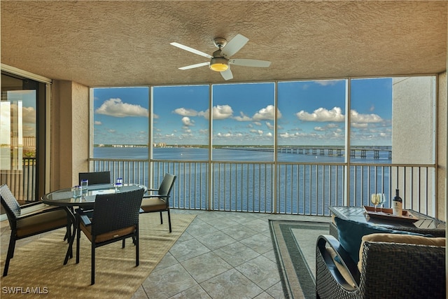 sunroom with a water view and ceiling fan