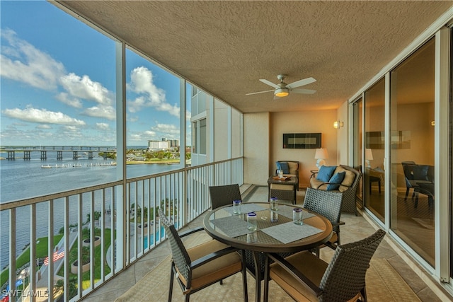 sunroom featuring ceiling fan and a water view