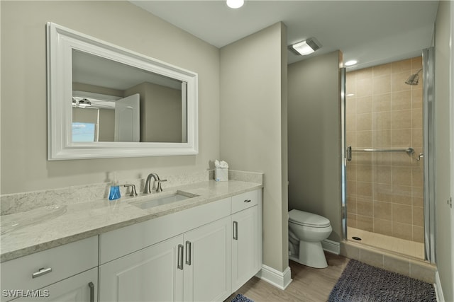 bathroom with hardwood / wood-style floors, vanity, a shower with shower door, and toilet