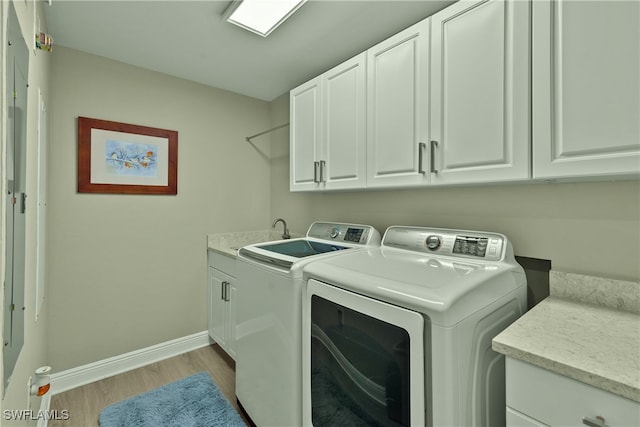 washroom with cabinets, independent washer and dryer, light hardwood / wood-style floors, and sink