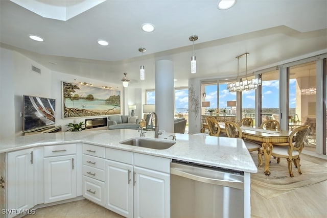 kitchen featuring light stone counters, white cabinetry, an inviting chandelier, sink, and stainless steel dishwasher