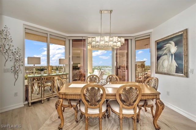 dining room with a chandelier, light wood-type flooring, and a wealth of natural light