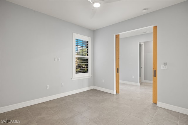 tiled spare room featuring ceiling fan