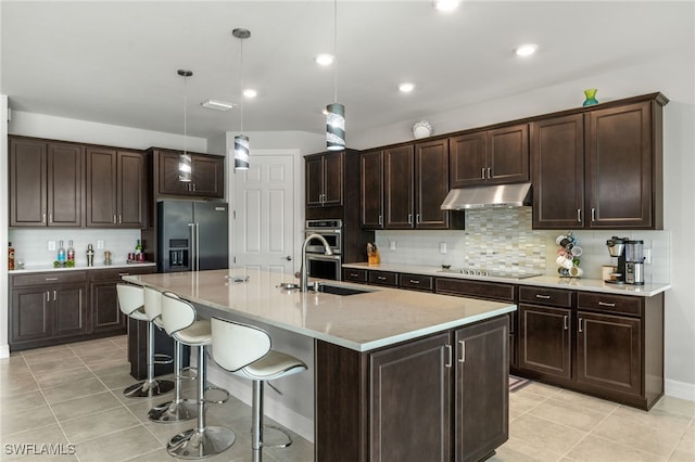 kitchen featuring stainless steel appliances, an island with sink, hanging light fixtures, and backsplash