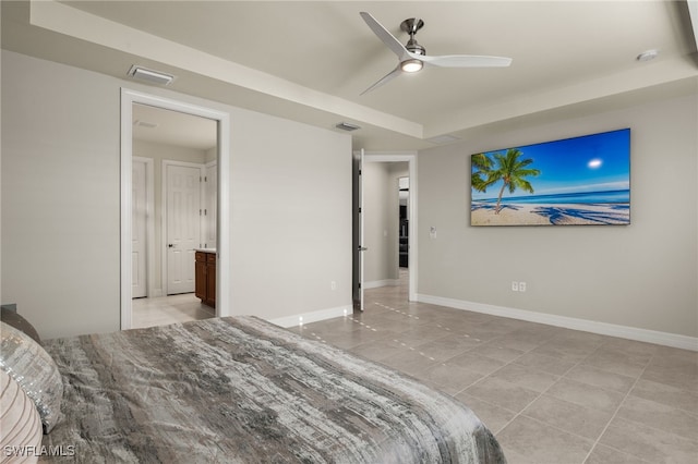 bedroom with ceiling fan, a raised ceiling, ensuite bath, and light tile patterned floors