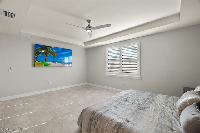 bedroom with a raised ceiling, light tile patterned flooring, and ceiling fan