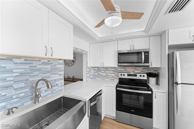 kitchen with light hardwood / wood-style floors, white cabinetry, sink, appliances with stainless steel finishes, and decorative backsplash