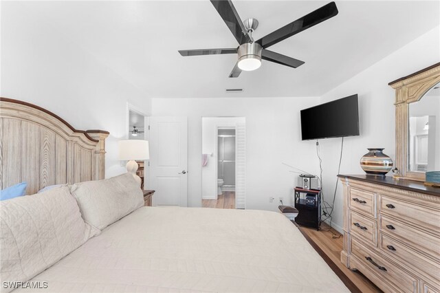 bedroom with ceiling fan, a walk in closet, light hardwood / wood-style floors, and ensuite bathroom