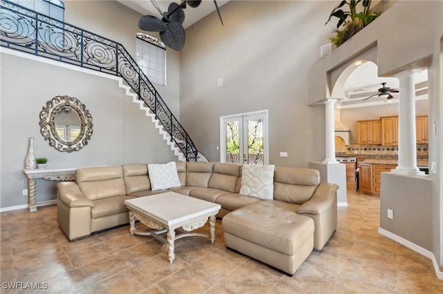 tiled living room featuring a high ceiling, decorative columns, and ceiling fan