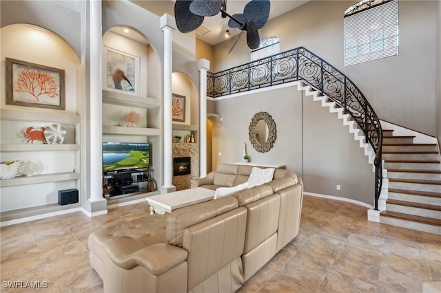 living room with built in shelves, a high ceiling, and ornate columns