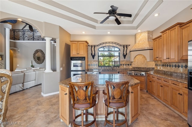 kitchen with decorative backsplash, stone counters, a center island, and decorative columns