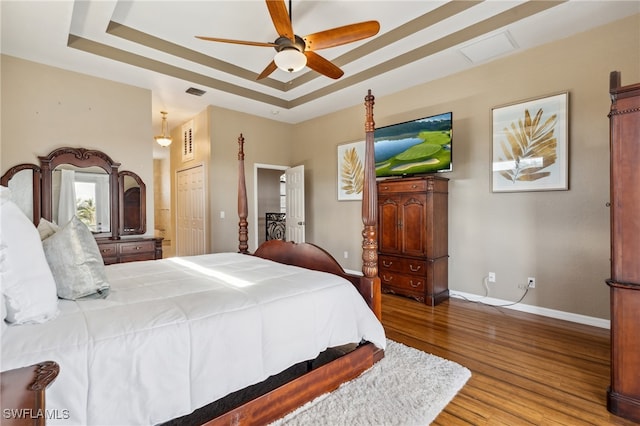 bedroom featuring hardwood / wood-style flooring, ceiling fan, a closet, and a raised ceiling