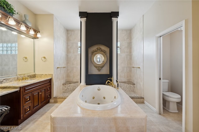 bathroom featuring tiled bath, vanity, ornate columns, tile patterned flooring, and toilet