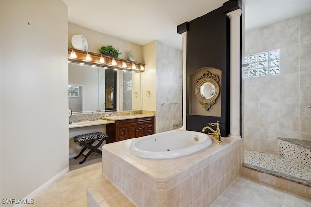 bathroom featuring tile patterned floors, vanity, a relaxing tiled tub, and ornate columns