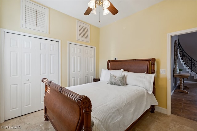 tiled bedroom with ceiling fan and two closets