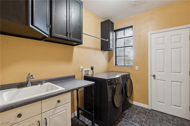 clothes washing area with cabinets, a textured ceiling, sink, and washing machine and clothes dryer