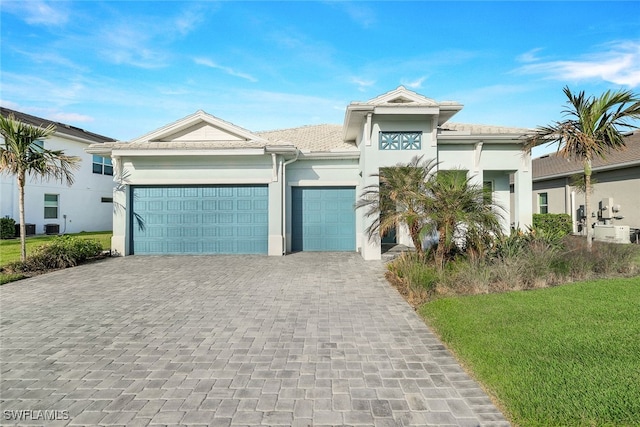 view of front of home featuring a garage, decorative driveway, central AC unit, and stucco siding