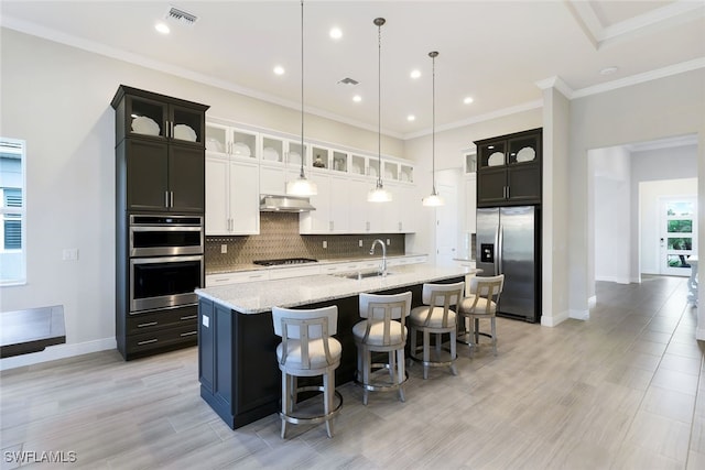 kitchen featuring extractor fan, pendant lighting, an island with sink, sink, and stainless steel appliances