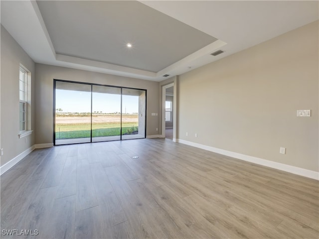 spare room featuring light hardwood / wood-style floors and a tray ceiling