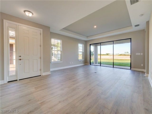 foyer entrance with a raised ceiling and light hardwood / wood-style flooring