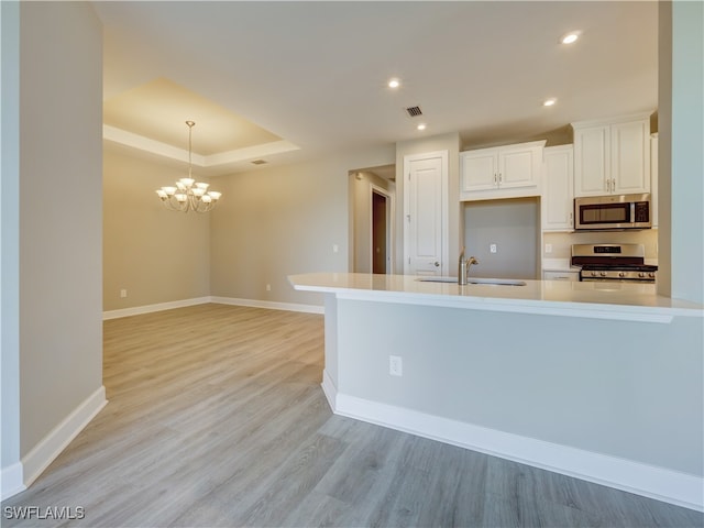 kitchen with white cabinetry, sink, hanging light fixtures, light hardwood / wood-style floors, and appliances with stainless steel finishes