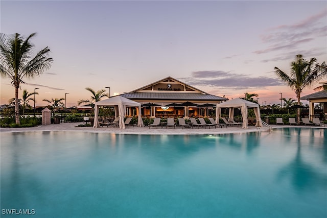 pool at dusk featuring a gazebo