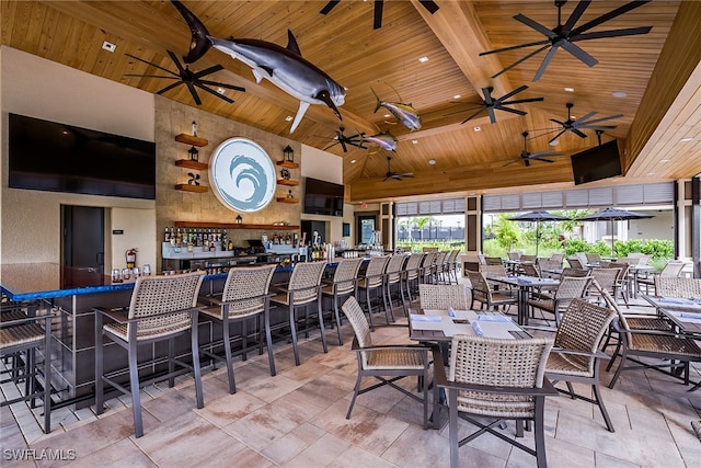 dining space featuring beamed ceiling, wooden ceiling, high vaulted ceiling, and bar