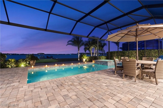 pool at dusk with an in ground hot tub, a lanai, and a patio area