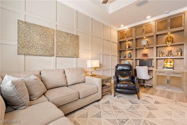 living room featuring built in shelves, ornamental molding, and light hardwood / wood-style flooring