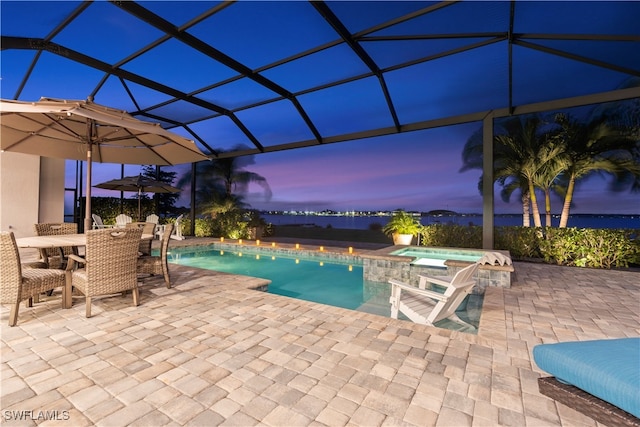 pool at dusk featuring an in ground hot tub, a patio, and a lanai