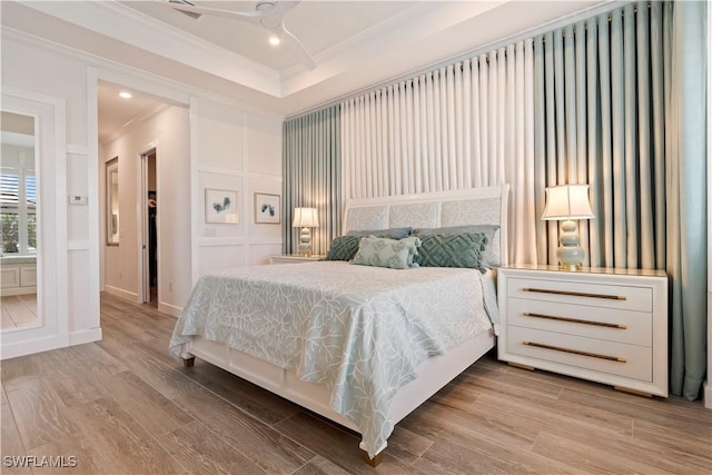 bedroom with ornamental molding, a raised ceiling, and light hardwood / wood-style floors