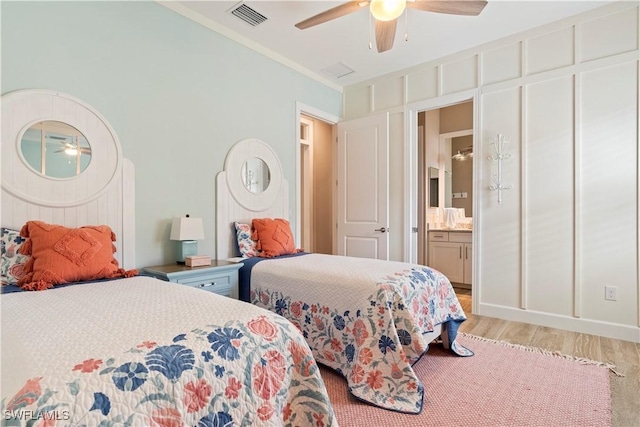 bedroom with ornamental molding, connected bathroom, ceiling fan, and light wood-type flooring