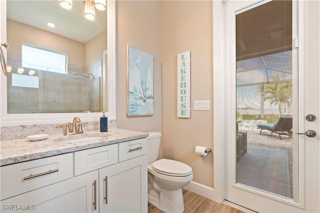 bathroom with vanity, wood-type flooring, a tile shower, and toilet