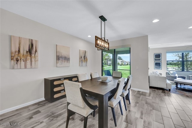 dining area featuring light hardwood / wood-style floors and ceiling fan with notable chandelier