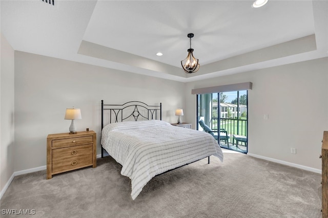 carpeted bedroom with a raised ceiling, access to outside, and an inviting chandelier