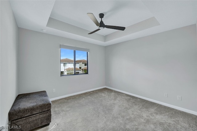 unfurnished room featuring carpet, a raised ceiling, and ceiling fan