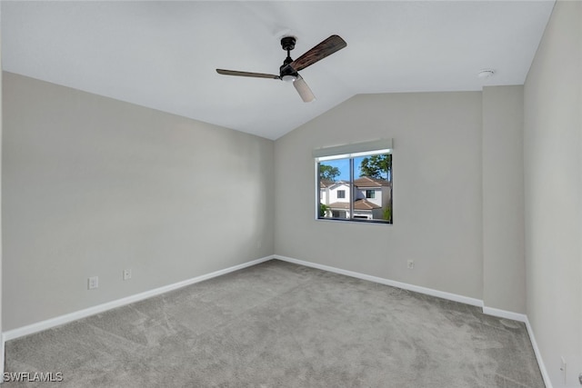 carpeted spare room with ceiling fan and vaulted ceiling