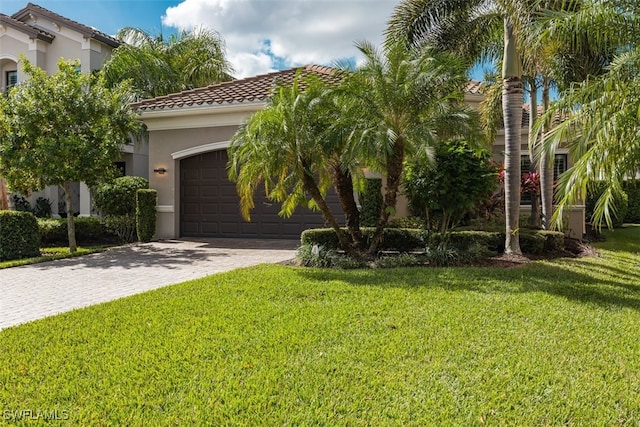 mediterranean / spanish home with decorative driveway, stucco siding, a garage, a tiled roof, and a front lawn