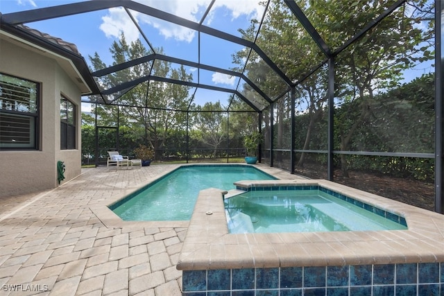 view of swimming pool with glass enclosure, a patio area, and a pool with connected hot tub