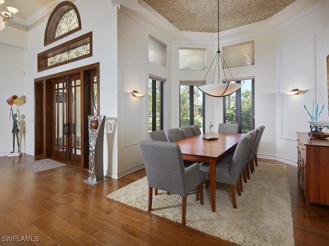 dining area featuring crown molding, a high ceiling, and dark hardwood / wood-style flooring