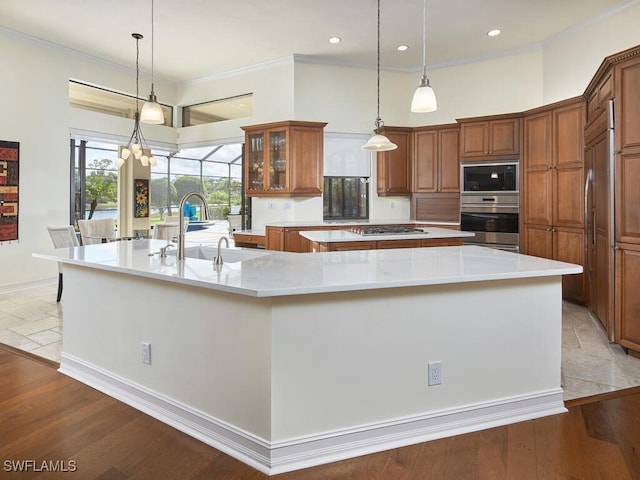 kitchen with a spacious island, hanging light fixtures, appliances with stainless steel finishes, and sink