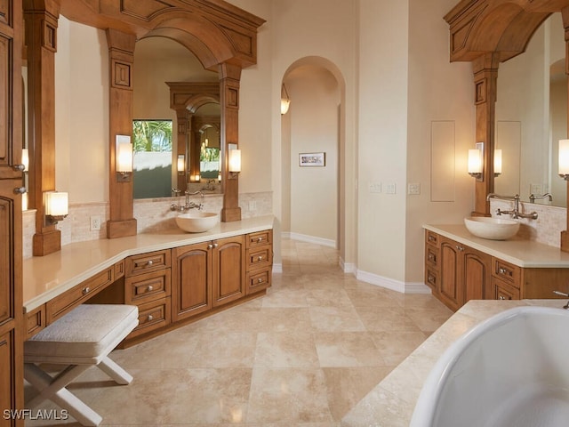 bathroom with decorative columns, a tub to relax in, and vanity