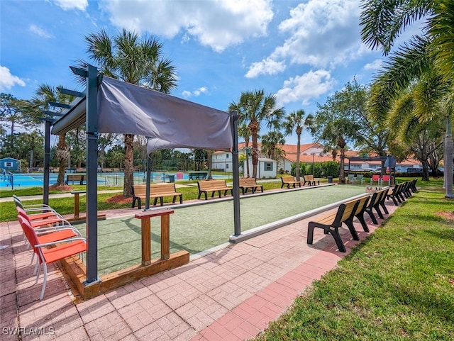 view of community featuring tennis court and a yard