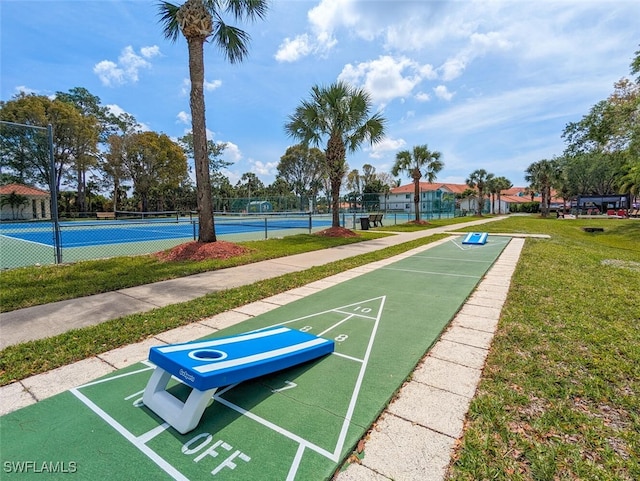 view of property's community with a lawn and tennis court