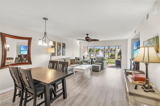 dining space featuring ceiling fan with notable chandelier and light wood-type flooring