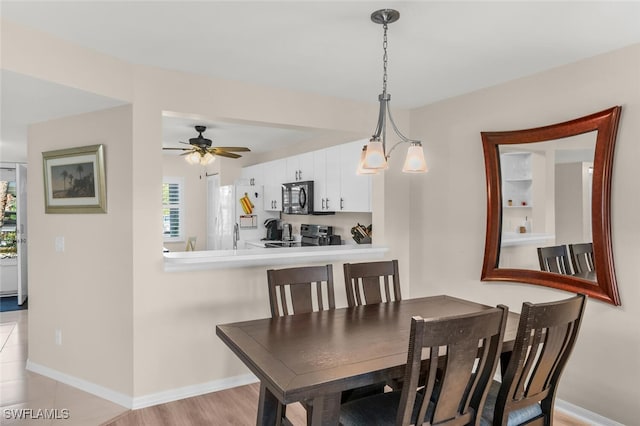 dining area with ceiling fan with notable chandelier and light wood-type flooring