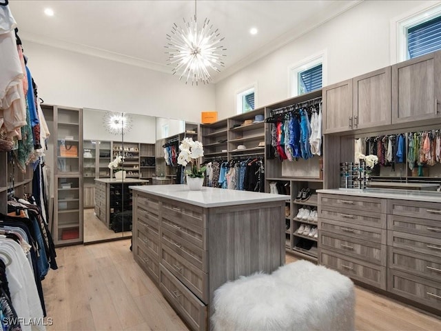 walk in closet with light wood-type flooring and an inviting chandelier